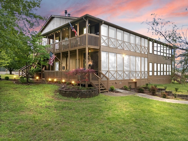 back of property at dusk featuring a lawn, crawl space, and stairway
