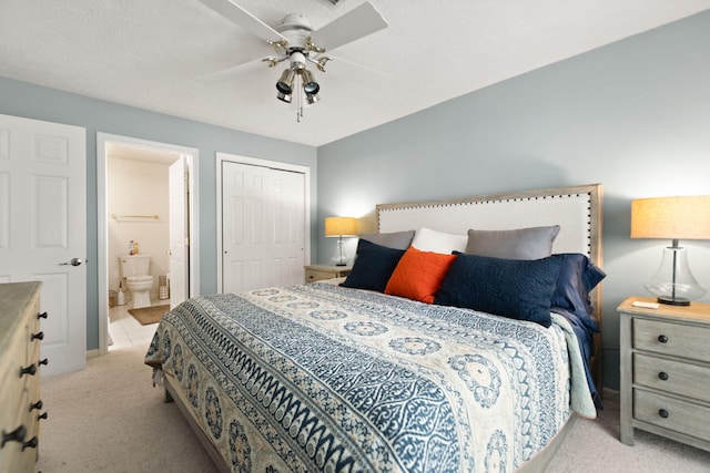 bedroom with a closet, light carpet, ensuite bathroom, baseboards, and ceiling fan