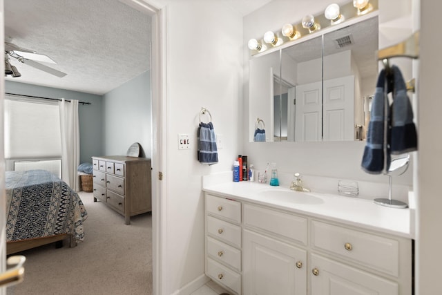bathroom featuring a ceiling fan, a textured ceiling, visible vents, vanity, and ensuite bath