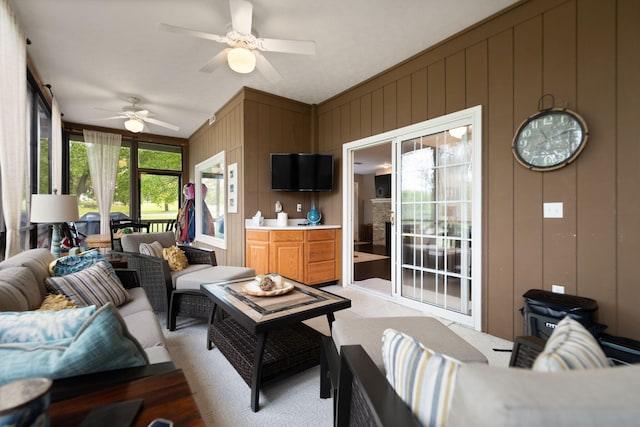 living room featuring a ceiling fan, light colored carpet, and a decorative wall