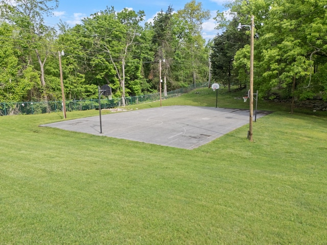 view of basketball court featuring a lawn, fence, and community basketball court