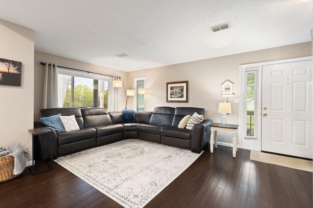 living area with plenty of natural light, dark wood-style floors, and visible vents