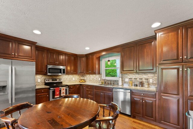 7314 Blue Level Rd, Rockfield, KY 42274 - kitchen with appliances with stainless steel finishes, light stone counters, a sink, light wood-style flooring, and decorative backsplash