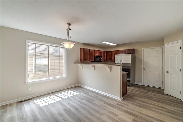 1148 Oatlands Park, Lexington, KY 40509 - kitchen featuring a breakfast bar area, visible vents, black microwave, a peninsula, and stainless steel fridge
