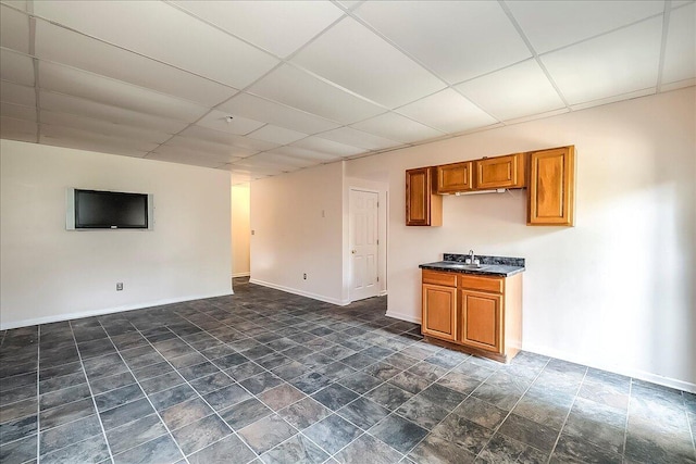 1148 Oatlands Park, Lexington, KY 40509 - unfurnished living room with a sink, baseboards, stone finish floor, and a paneled ceiling