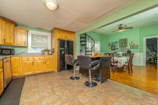 363 S Main St, Winchester, KY 40391 - kitchen featuring a textured ceiling, dishwashing machine, black refrigerator with ice dispenser, light countertops, and a ceiling fan