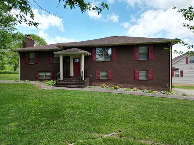 bi-level home with brick siding, a front lawn, and a chimney