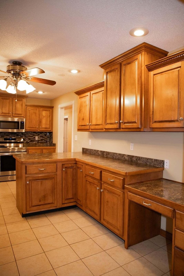 kitchen with ceiling fan, dark countertops, brown cabinetry, stainless steel appliances, and light tile patterned floors