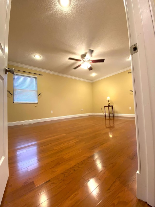 unfurnished room with crown molding, a textured ceiling, a ceiling fan, baseboards, and hardwood / wood-style flooring