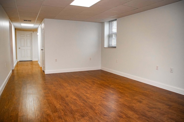 empty room with baseboards, visible vents, and dark wood finished floors