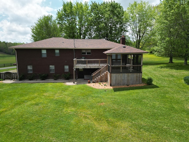 rear view of house with a wooden deck, a chimney, stairs, a sunroom, and a yard