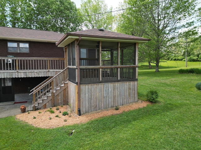 exterior space featuring roof with shingles, brick siding, a sunroom, stairway, and a lawn