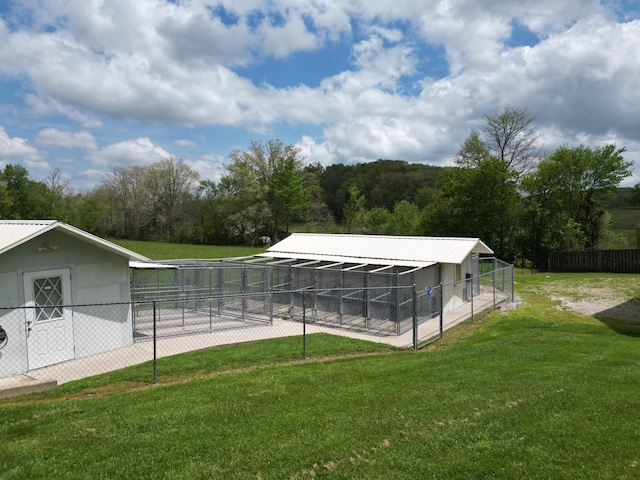 view of swimming pool featuring a lawn, fence, and an outbuilding