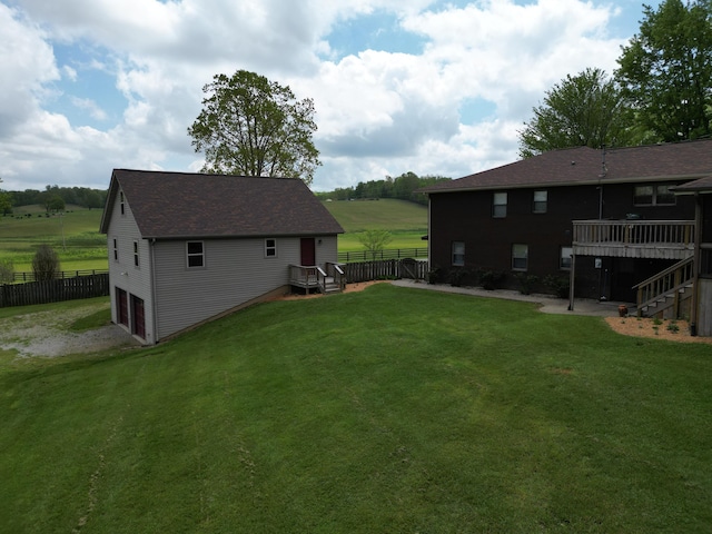 view of yard featuring an attached garage, stairway, fence, and a deck