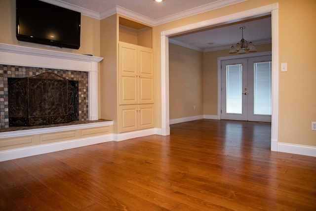 unfurnished living room with a notable chandelier, a fireplace, french doors, baseboards, and wood finished floors