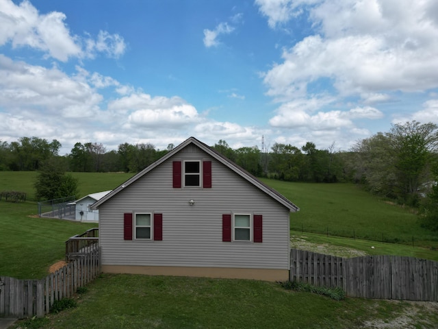 view of side of home with a lawn and fence