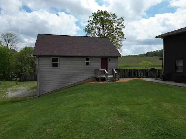 rear view of property with a lawn, fence, and a shingled roof