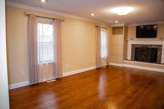 unfurnished living room featuring a fireplace with raised hearth, a textured ceiling, wood finished floors, and a healthy amount of sunlight