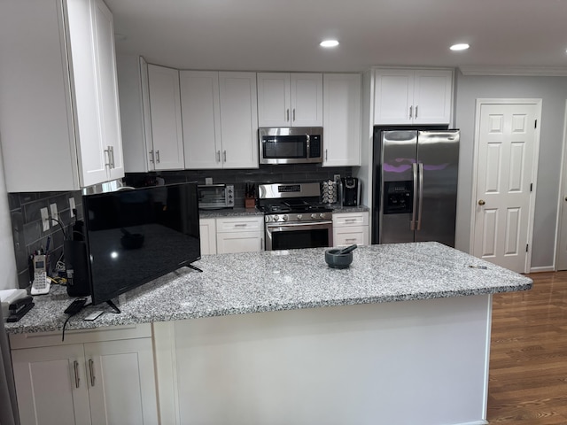 kitchen featuring appliances with stainless steel finishes, a peninsula, light stone counters, and white cabinetry
