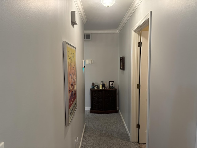 hallway featuring carpet flooring, baseboards, visible vents, and ornamental molding