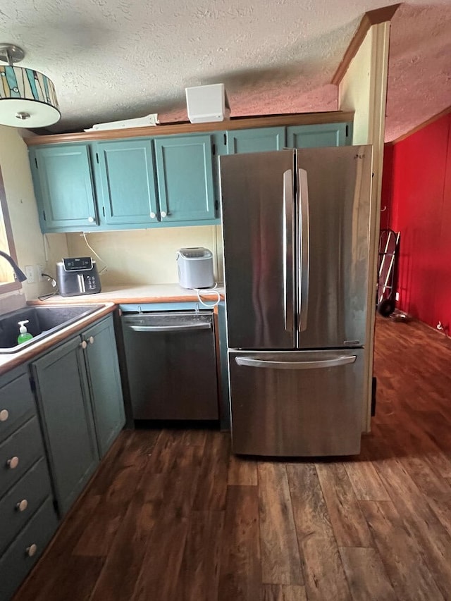 kitchen featuring dark wood-type flooring, a sink, a textured ceiling, and stainless steel appliances