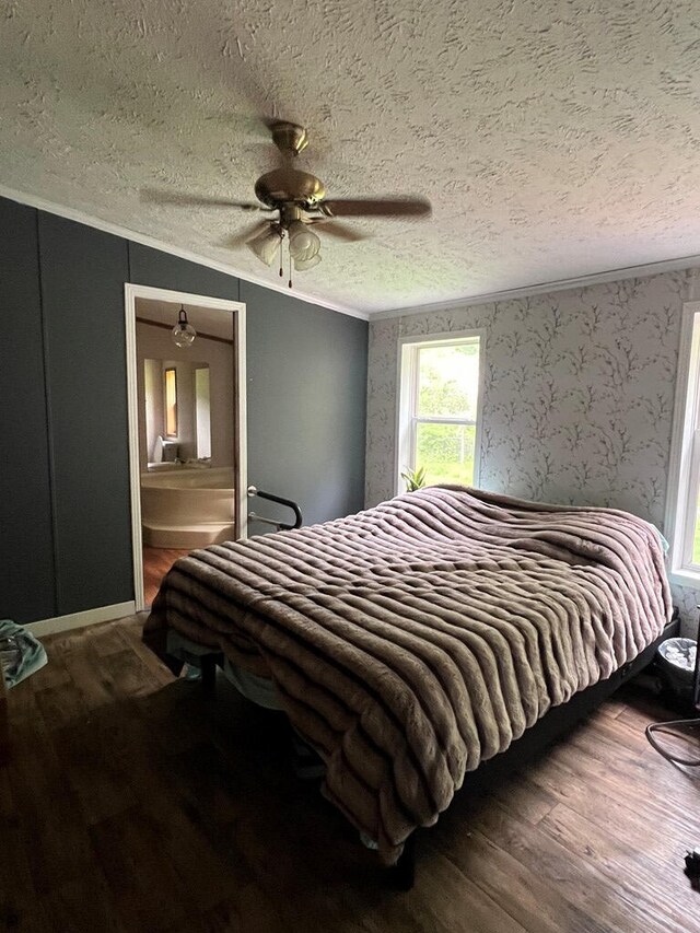 bedroom with a ceiling fan, a textured ceiling, crown molding, wood finished floors, and connected bathroom