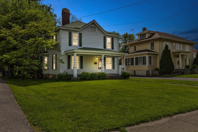 view of front of home with covered porch, a chimney, and a front lawn