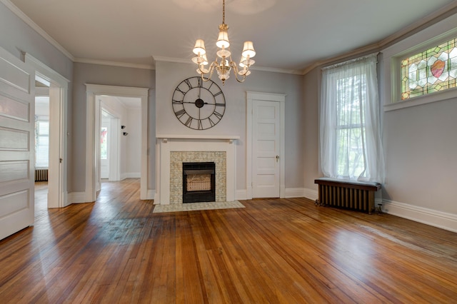 unfurnished living room featuring ornamental molding, radiator heating unit, a chandelier, and hardwood / wood-style floors