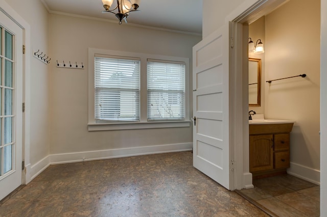 interior space with crown molding, a sink, and baseboards