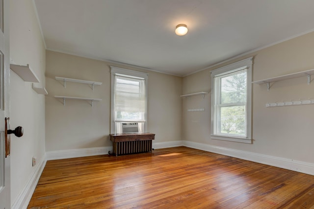 empty room featuring radiator, baseboards, wood-type flooring, and cooling unit