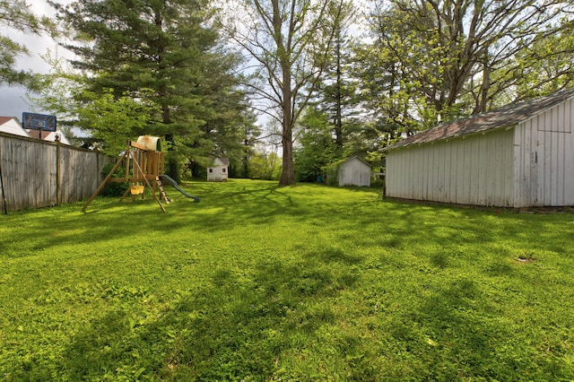 view of yard with a playground, a storage unit, an outdoor structure, and fence