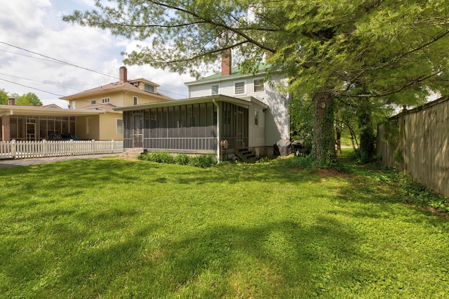 back of property featuring a sunroom, a lawn, fence, and a chimney
