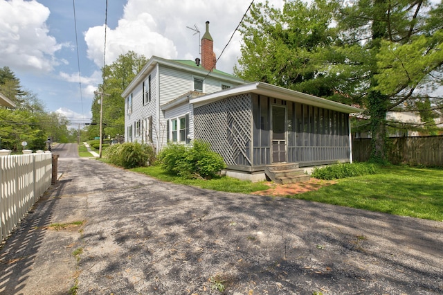 view of property exterior featuring fence, a chimney, and a sunroom