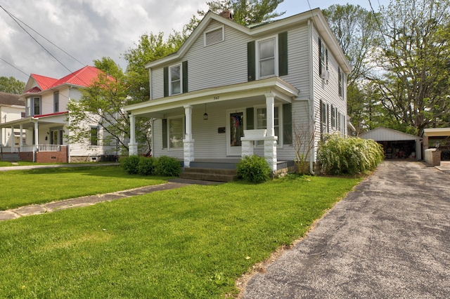 view of front of home featuring covered porch, a front yard, a chimney, an outbuilding, and a detached garage