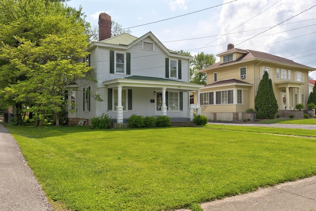 view of front of house with covered porch, a chimney, and a front lawn