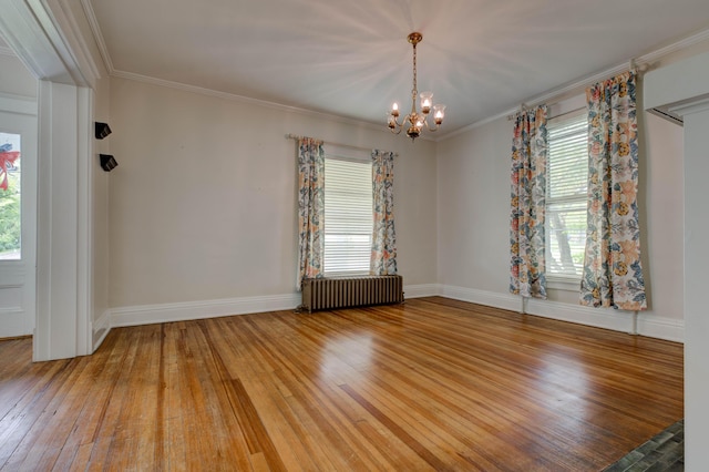empty room featuring hardwood / wood-style flooring, a notable chandelier, plenty of natural light, and radiator