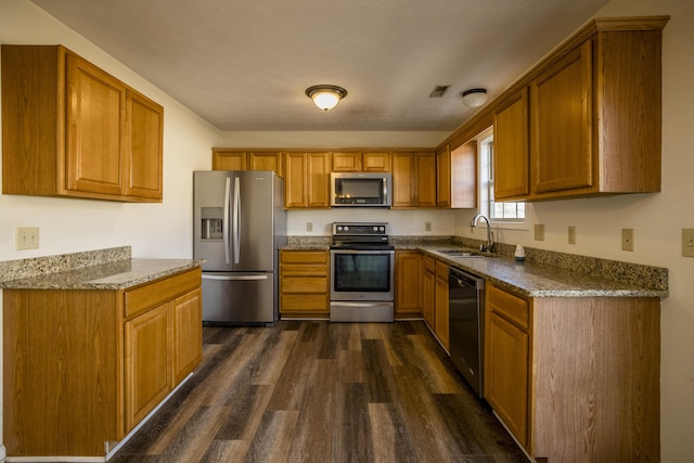 108 Sturbridge Ln, Winchester, KY 40391 - kitchen with stainless steel appliances, a sink, dark wood-style flooring, brown cabinets, and dark stone counters