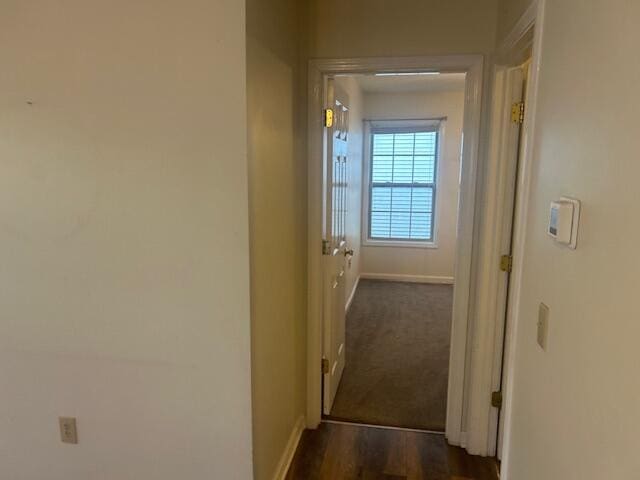 corridor with baseboards and dark wood-type flooring