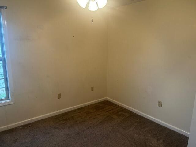 empty room featuring baseboards, a ceiling fan, and dark colored carpet