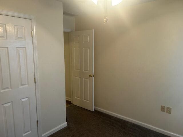 interior space with baseboards and dark carpet