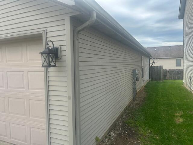 view of home's exterior featuring a garage, fence, and a lawn