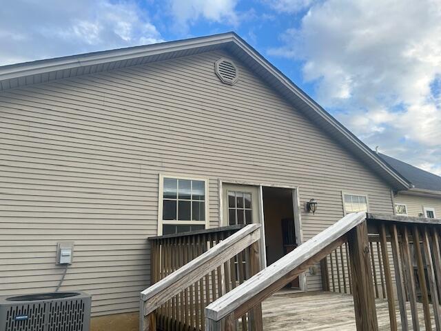 rear view of property with cooling unit and a deck