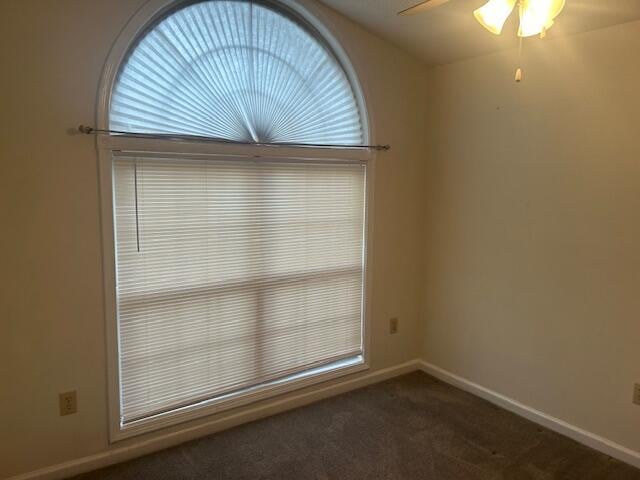 spare room with dark carpet, plenty of natural light, ceiling fan, and baseboards