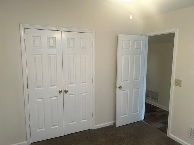 unfurnished bedroom with a closet, baseboards, visible vents, and dark colored carpet