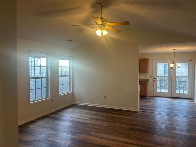 unfurnished living room featuring baseboards, dark wood-style flooring, and a wealth of natural light