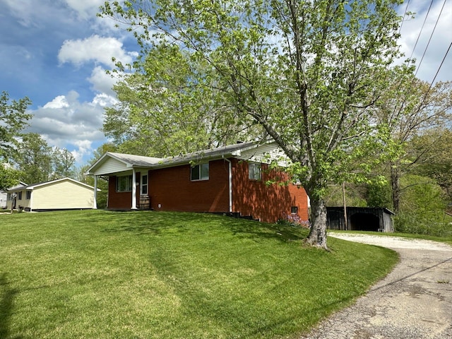 view of property exterior featuring dirt driveway, a yard, and brick siding