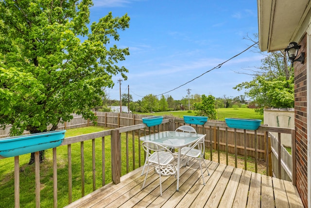 wooden deck with a fenced backyard, outdoor dining area, and a yard