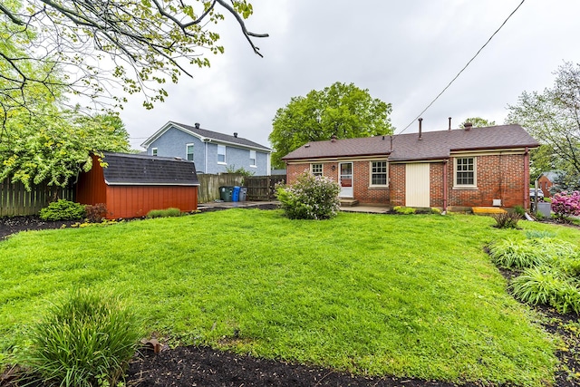 back of house with brick siding, fence, an outdoor structure, and a storage unit