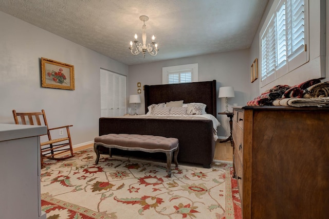 bedroom with a textured ceiling, baseboards, and a notable chandelier