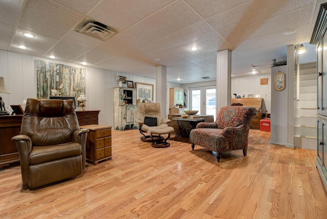 living area with light wood-type flooring, a paneled ceiling, and visible vents